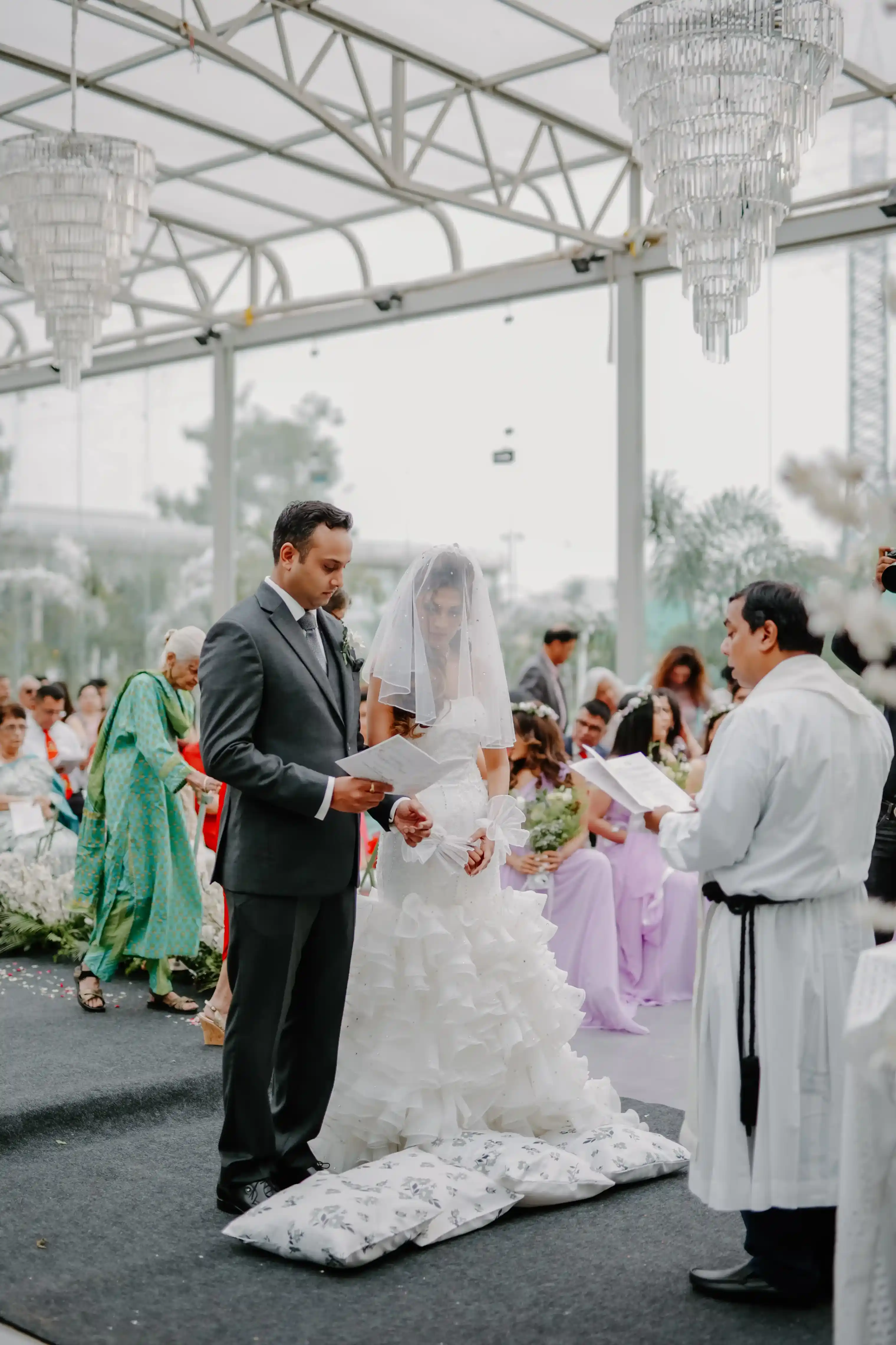Bride Rebecca and groom Akshaan face each other at the altar, reading their personal vows during the ceremony.